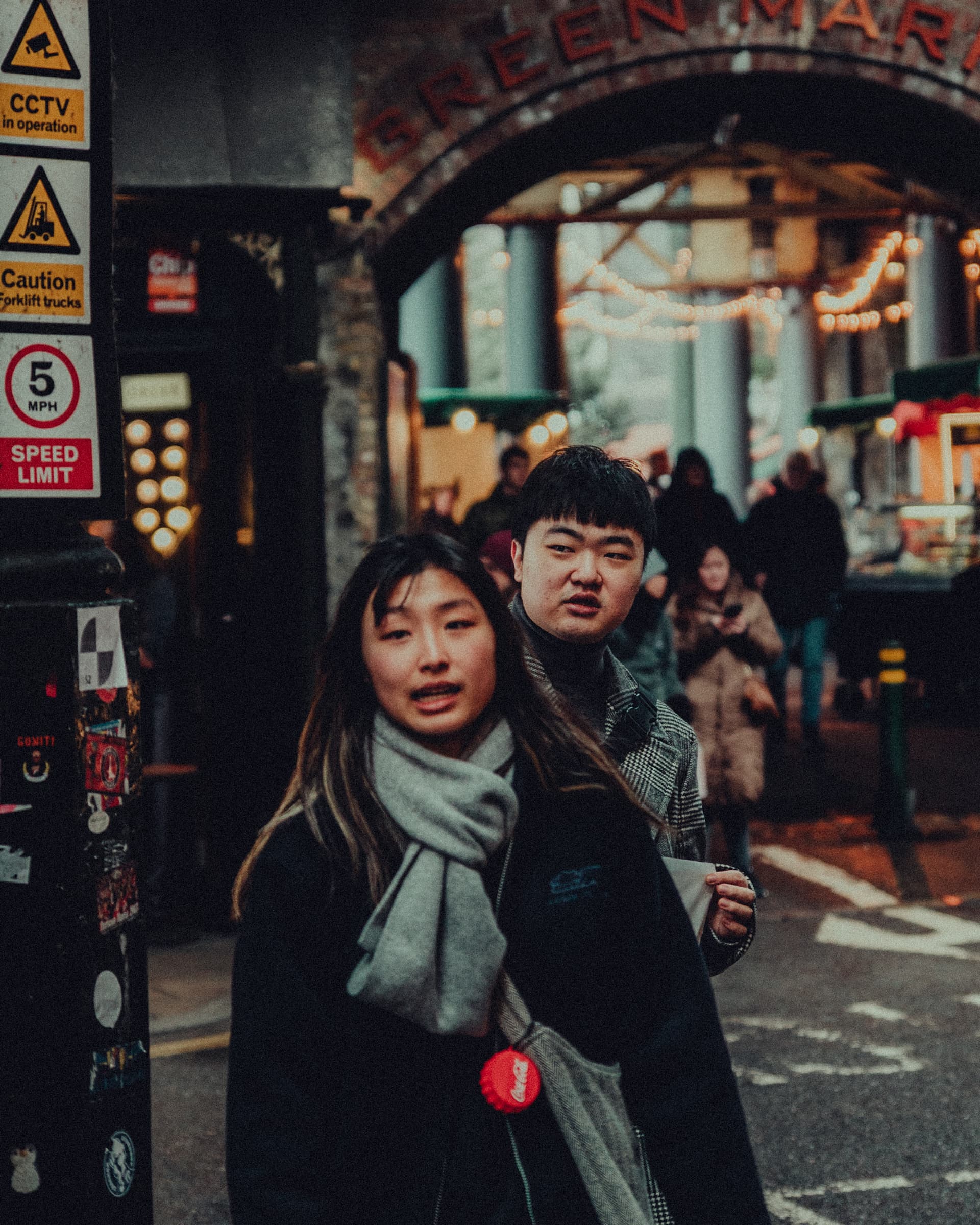 Two young people walking towards the camera beneath an arched market entrance