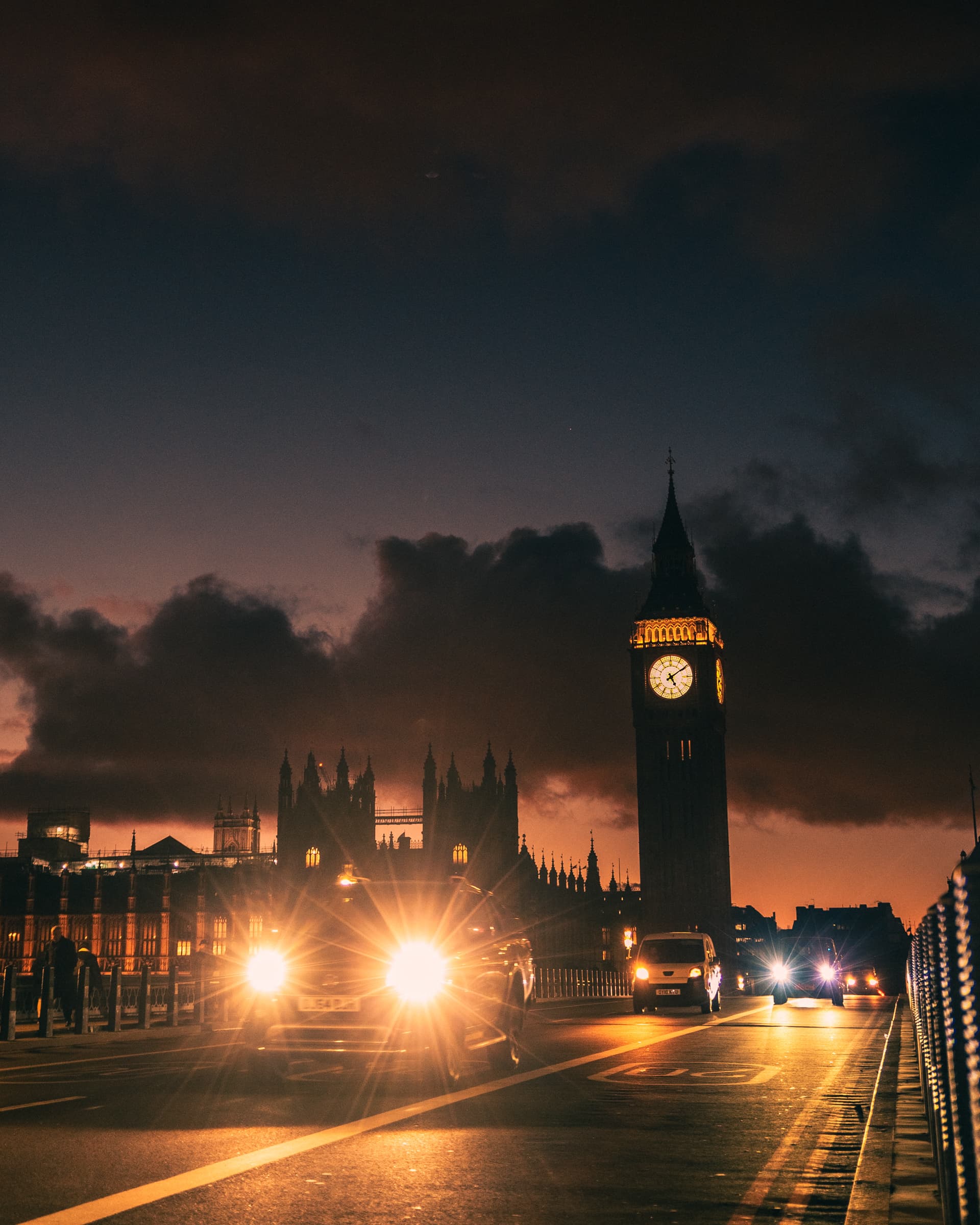 Big Ben and the Houses of Parliament in London at dusk, headlights on the road