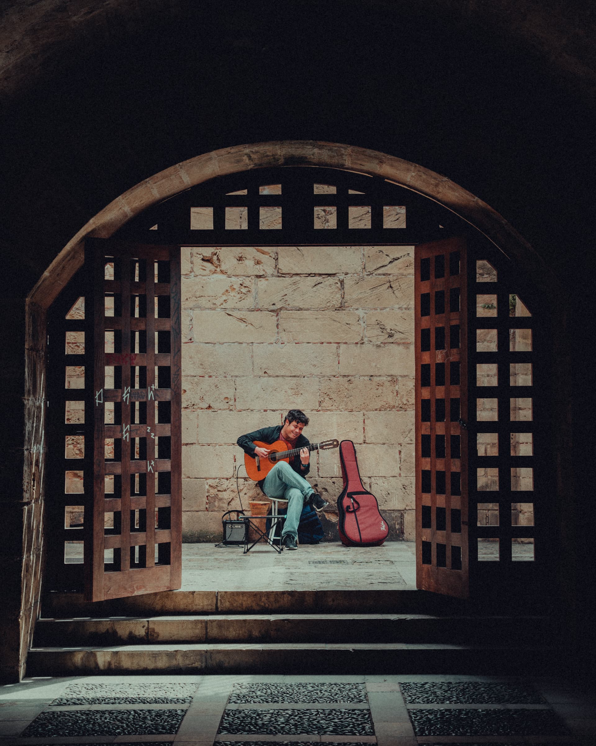 Busker with a guitar playing inside an arched wooden doorway in Palma, Majorca