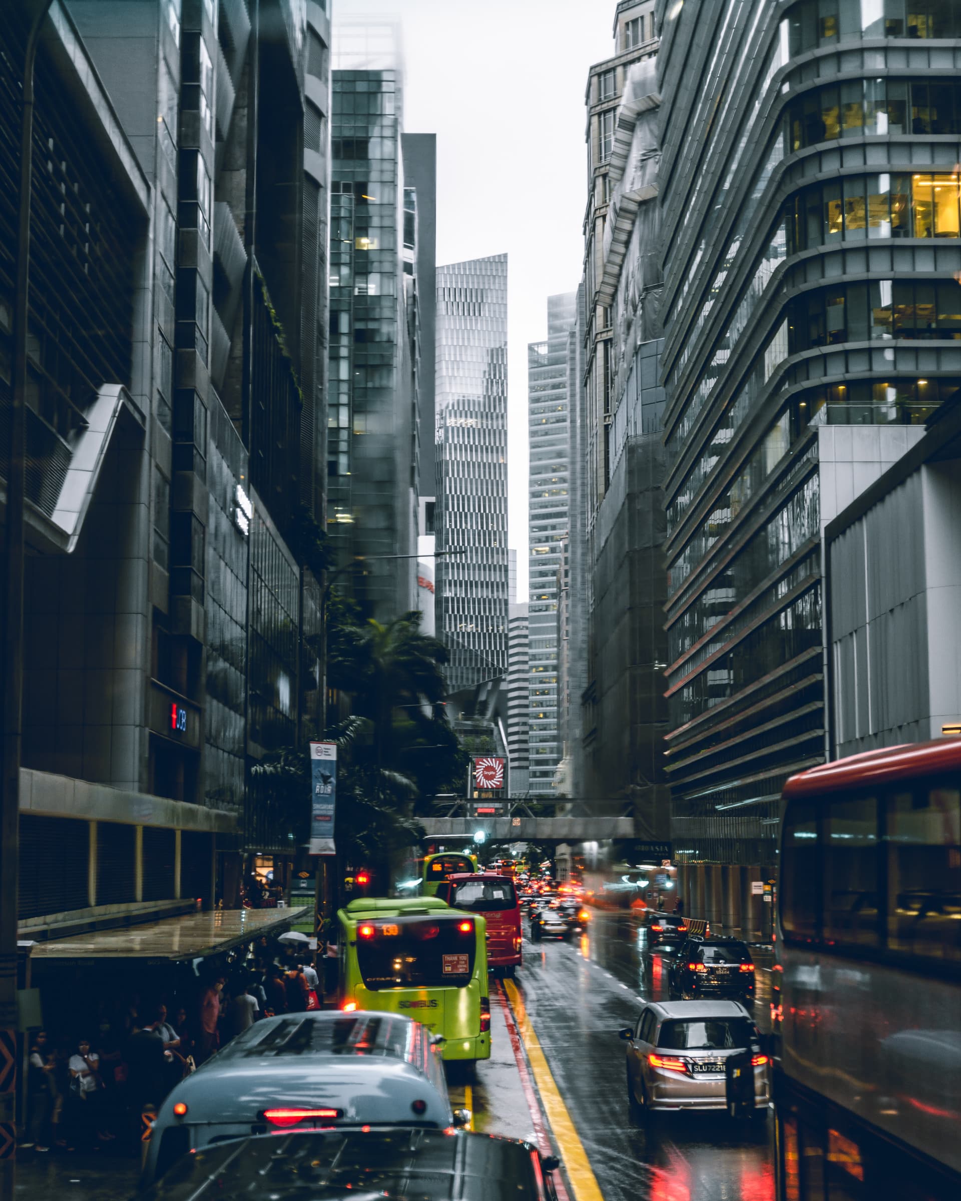 Traffic and buses on a rainy street between skyscrapers in Singapore