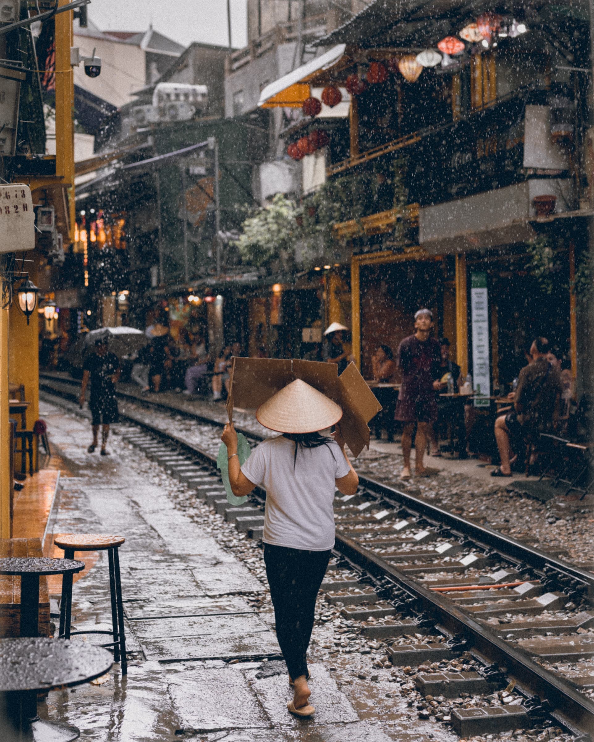 Woman in a conical hat walking along the tracks of Hanoi's Train Street