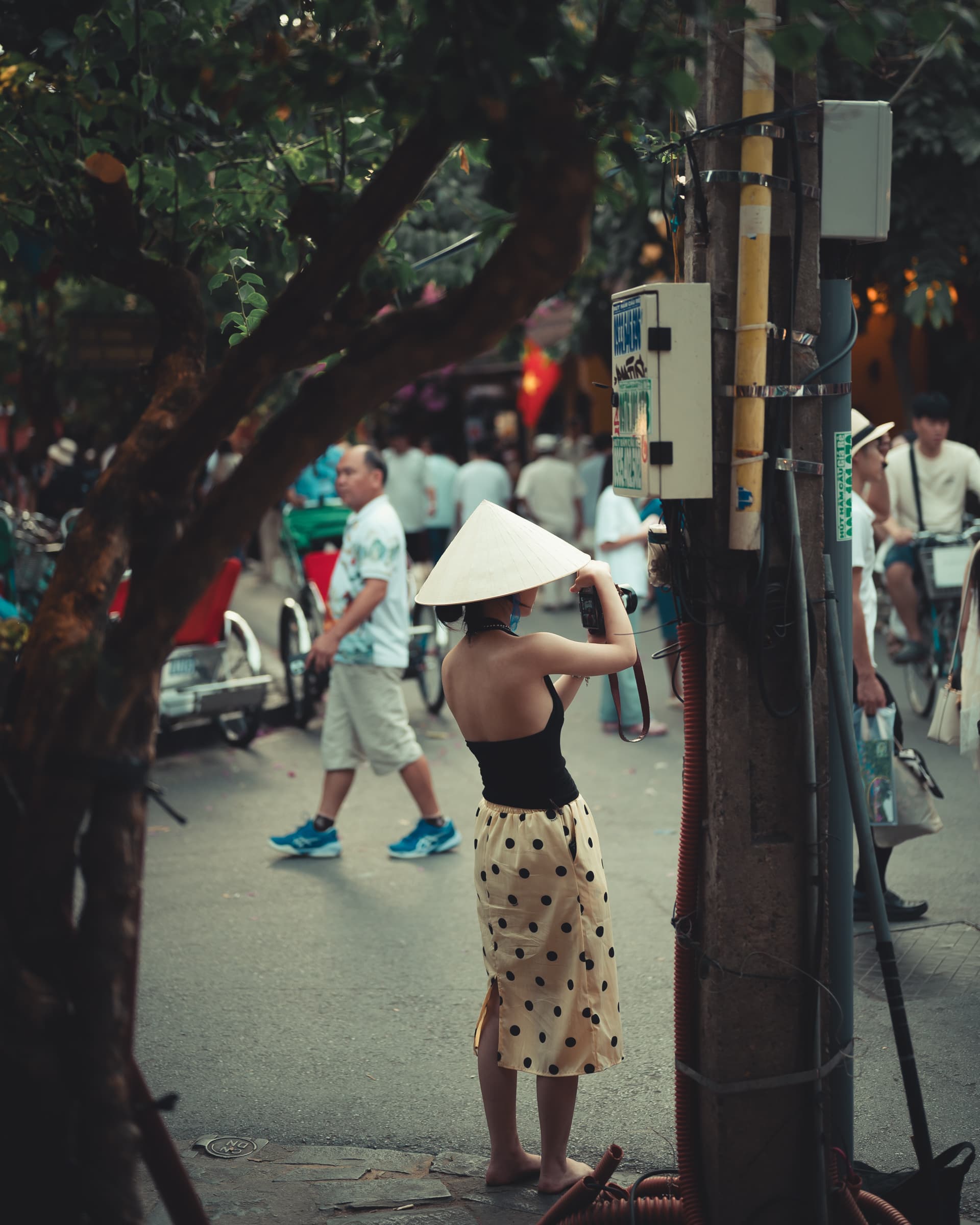 Woman in a conical hat and polka dot skirt on a busy street