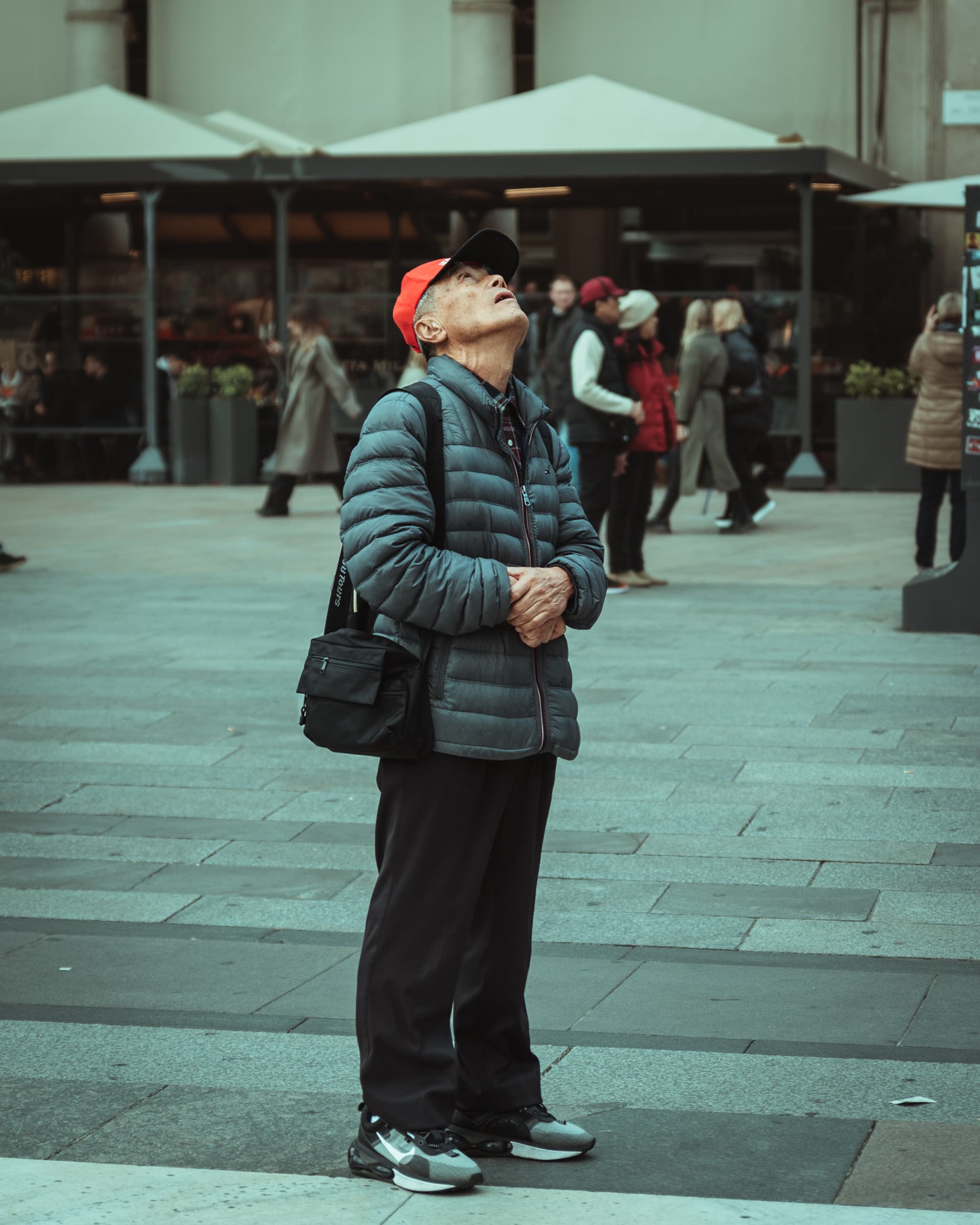 Man in a red cap looking up in a city square